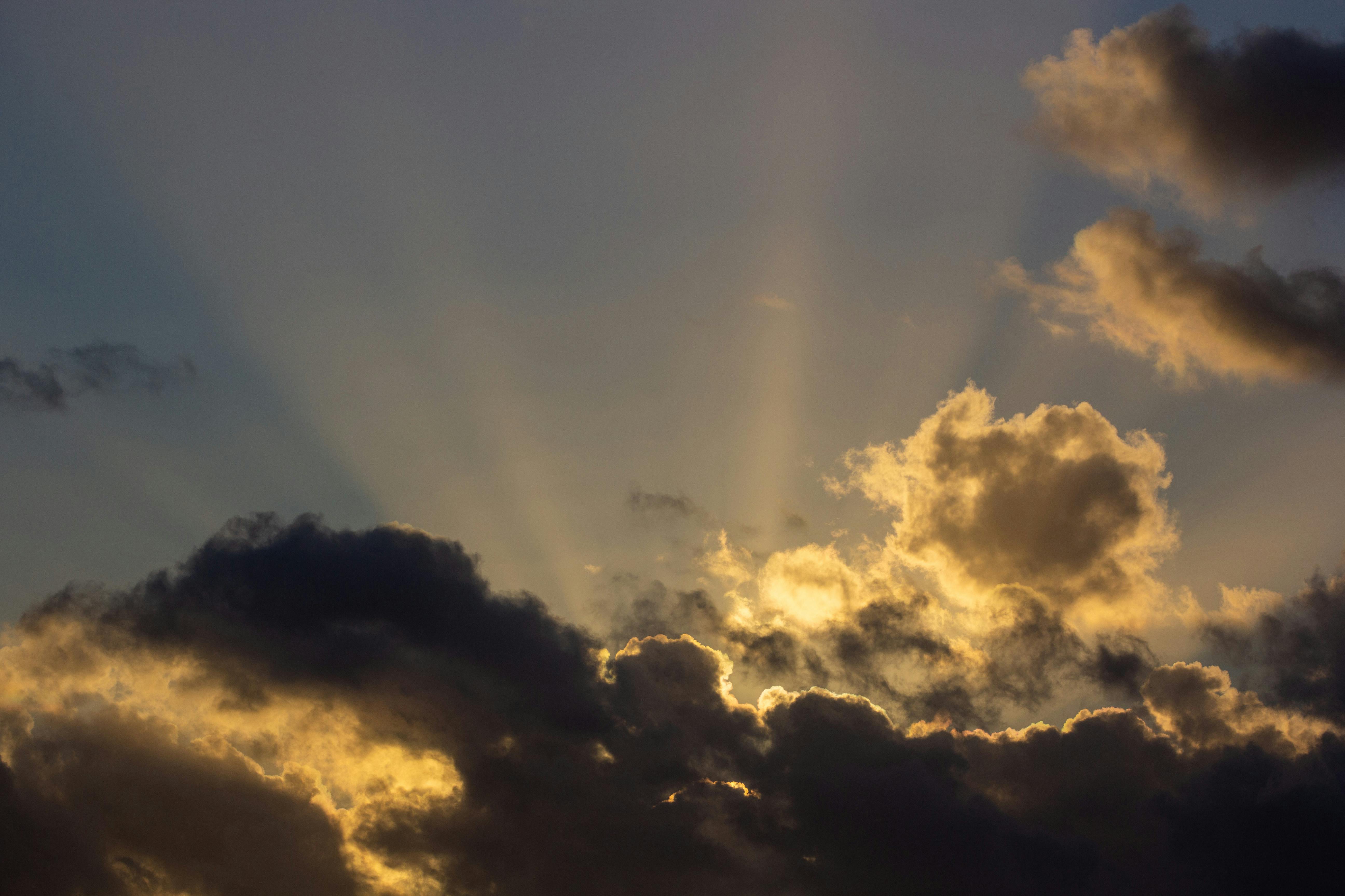 alt="Rayons de lumière traversant les nuages sombres, évoquant l'espoir après la tempête émotionnelle"