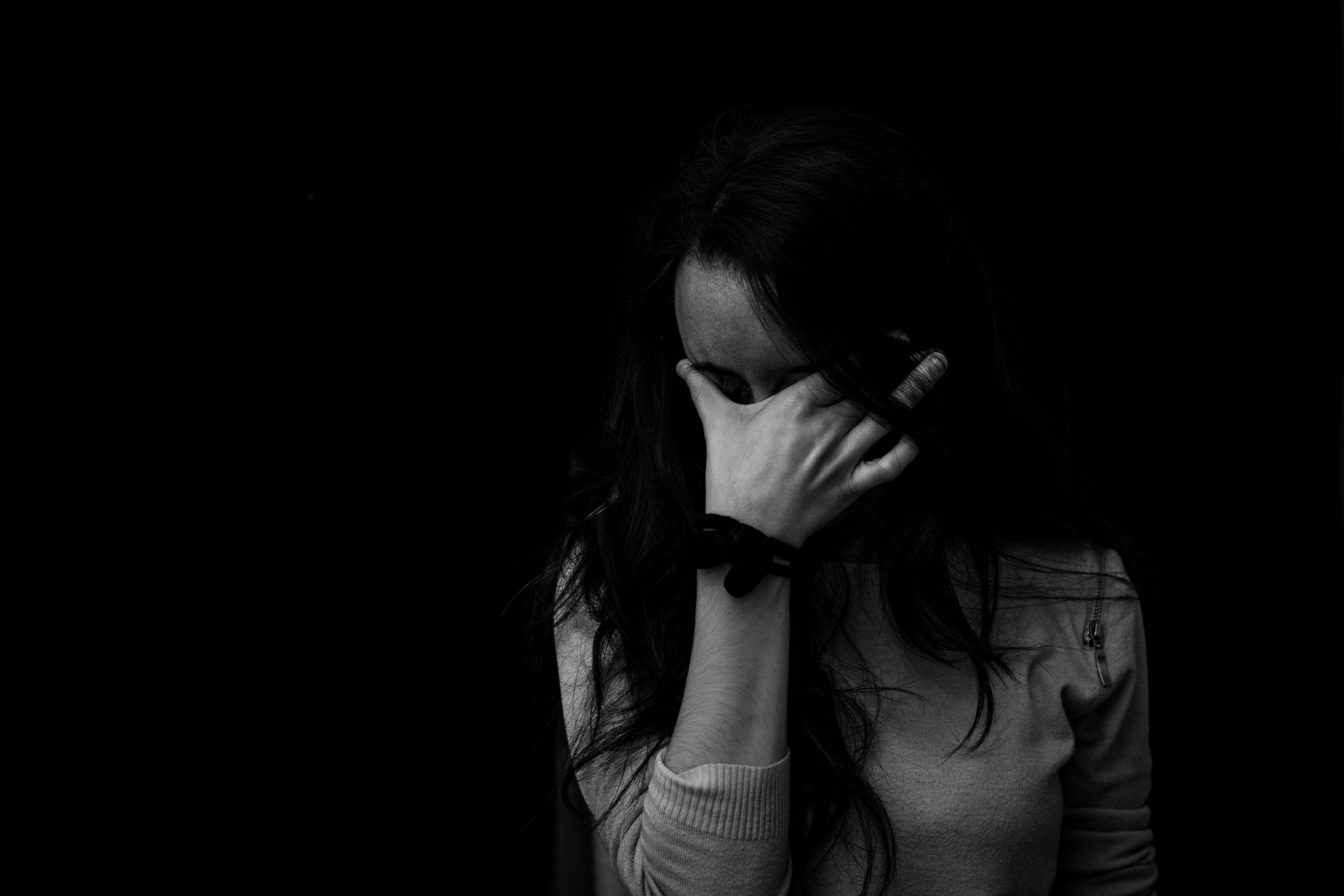 alt="femme seule, cachant son visage avec sa main, représentant une douleur intérieure et un repli émotionnel"