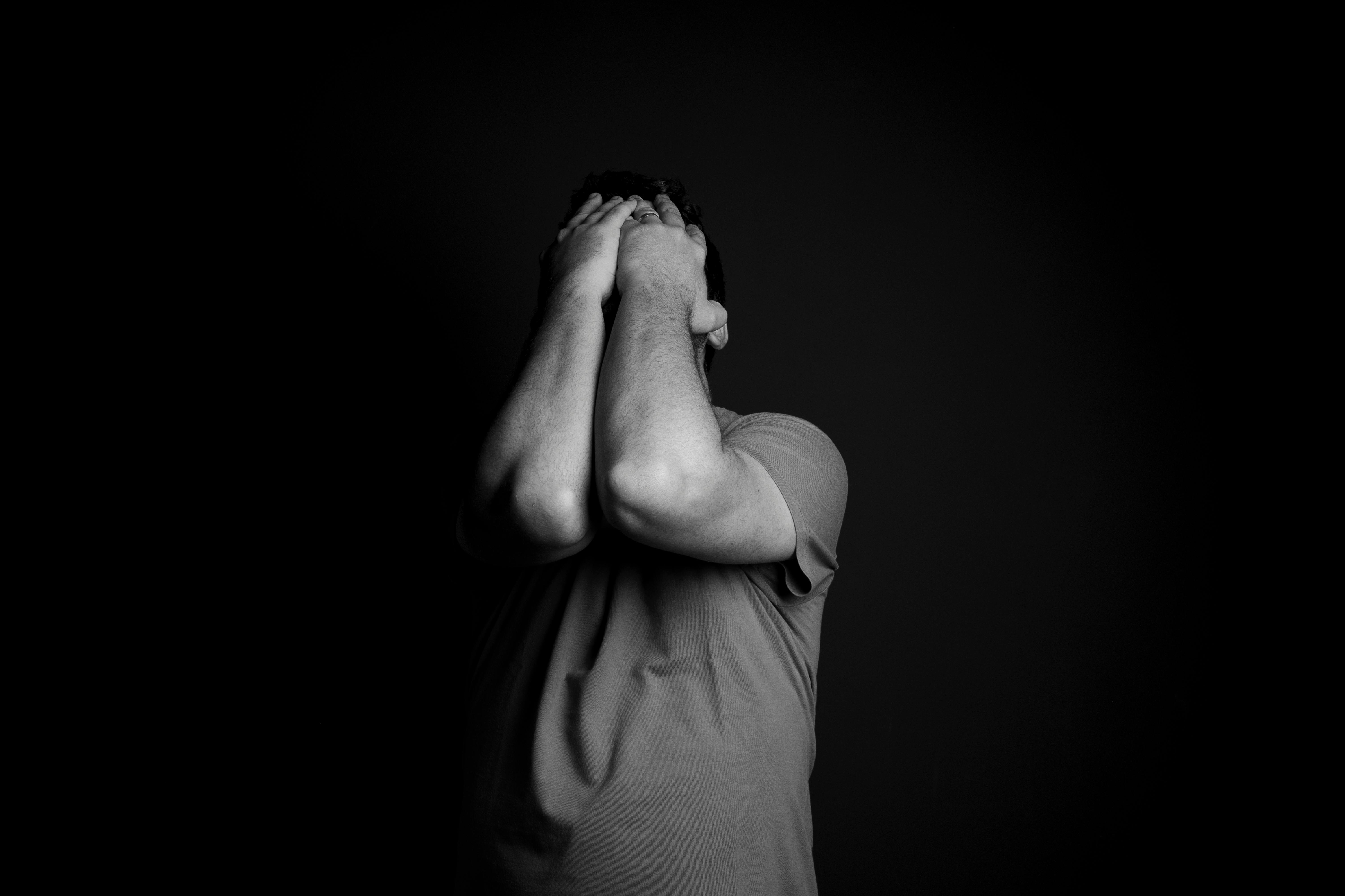 alt="Homme en détresse couvrant le visage avec les mains, représentant la souffrance émotionnelle masculine"
